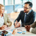 Serious businessman explaining principles of work to his colleagues at meeting