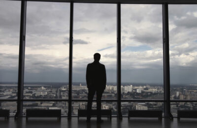 Rear view of man in formal suites who stand in front of panoramic window with city view. a man stands in front of big panoramic wiindow view from back HD